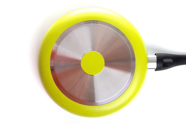 Bottom of a stylish modern lemoncolored frying pan with a metal disc on the bottom on a white