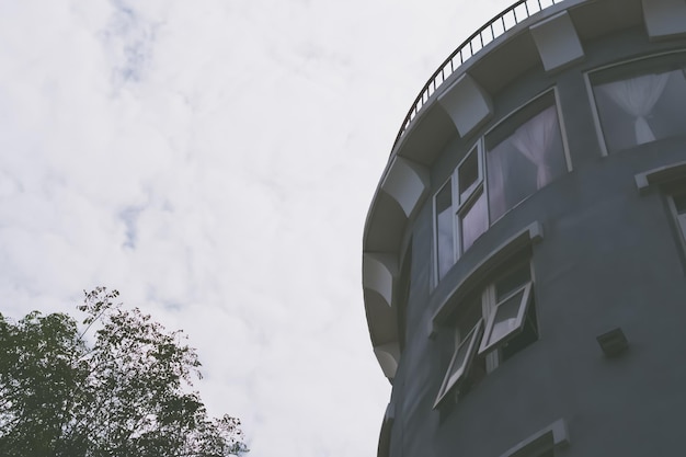 Bottom up view concrete gray modern sky tower building medieval fortress castle style Round Roof protrude brick metal railing large window Unusual architecture beauty solution urban construction dark