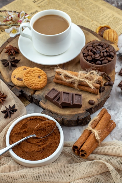 bottom view cup of coffee biscuits bowl with roasted coffee beans chocolate cinnamon sticks anises on wood board cocoa bowl on table