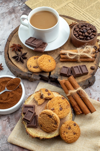 bottom view cup of coffee cookies bowl with roasted coffee beans chocolate cinnamon sticks anise stars on wood board cocoa bowl on table