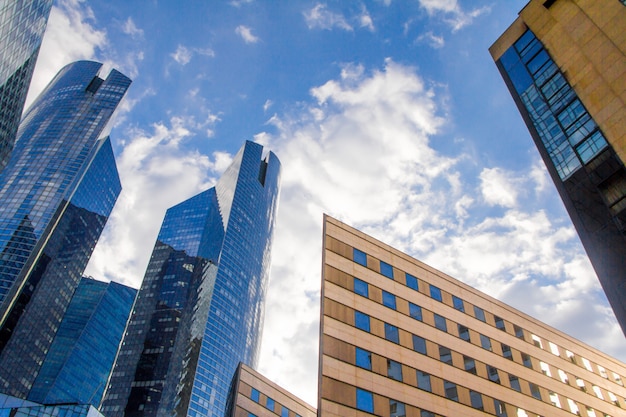 Bottom view of the glass skyscrapers of the business district of Paris La Defense against a blue cloudy sky