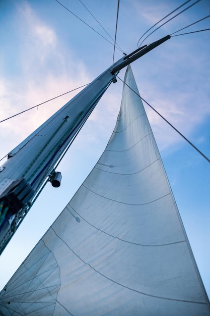 Bottom view mast boat against sky with cumulus clouds in sea Mast of sailing yacht with ropes with sail at blue sky background