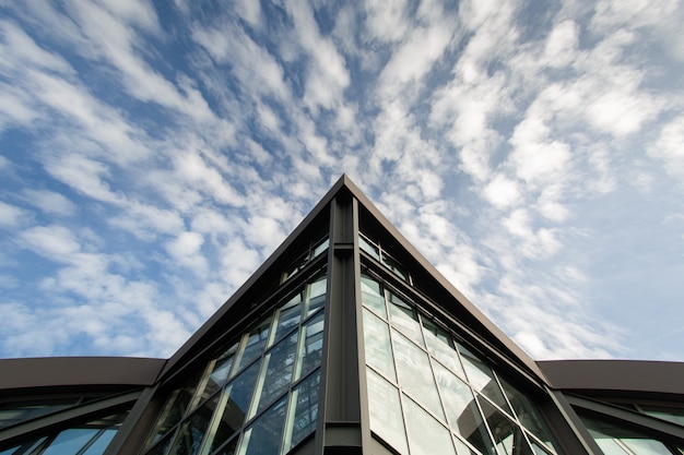 Bottom view of a modern building in Frankfurt. The sharp angle of building on sky background with white clouds. Copy space