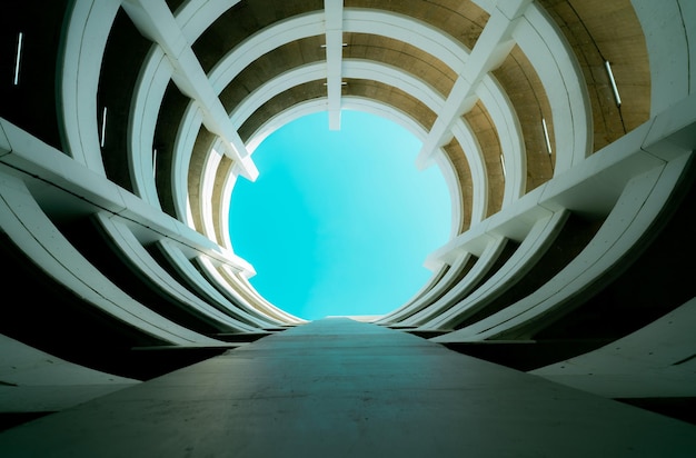 Bottom view multistory car park building with blue sky view in center Architecture of spiral