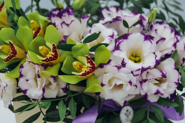 Bouquet of archidea and eustoma in a paper gift box on a gray background In purple white and yellow close up