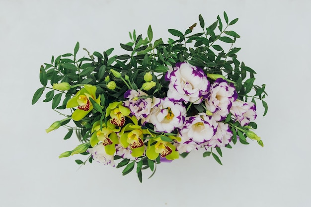 Bouquet of archidea and eustoma in a paper gift box on a gray background In purple white and yellow top view