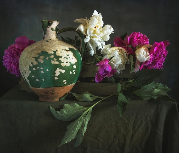 a bouquet of beautiful freshly cut peonies on the table and an old jug