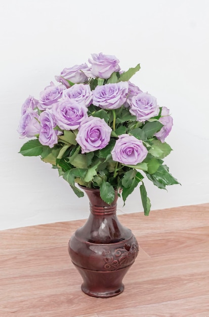 Bouquet of beautiful purple roses with water drops in a vase