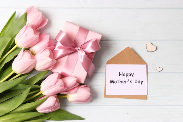 A bouquet of beautiful tulips and a card for text on a wooden background fork on top. Mother's day background, International Women's Day, birthday. Holiday, give. High quality photo