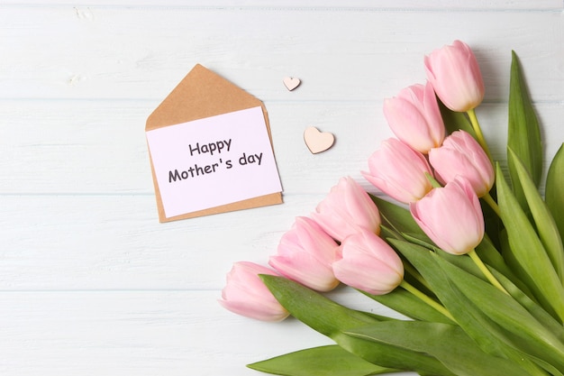 A bouquet of beautiful tulips and a card for text on a wooden background