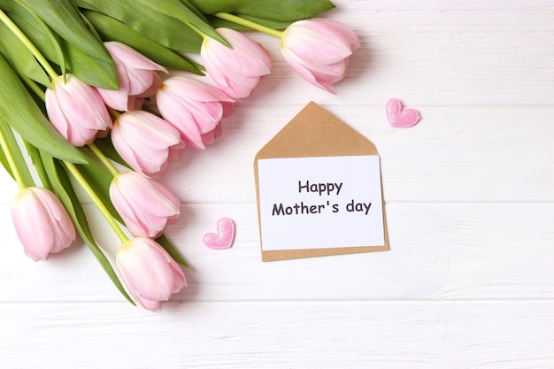 A bouquet of beautiful tulips and a card for text on a wooden background