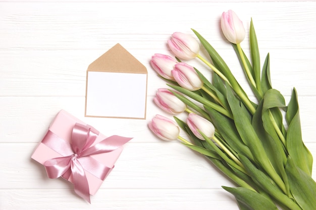 A bouquet of beautiful tulips and a gift on a wooden background top view. Mother's Day Background, International Women's Day. Holiday, give a gift. High quality photo