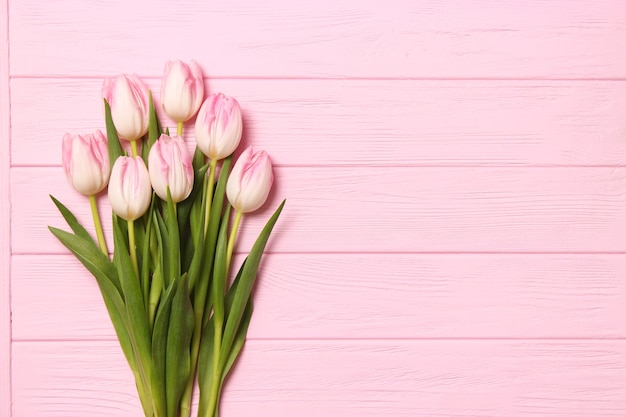 A bouquet of beautiful tulips and a gift on a wooden background top view