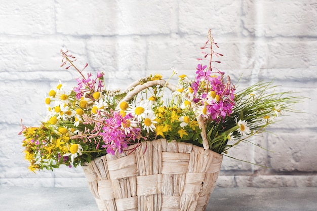 Bouquet of beautiful wildflowers in a basket on a gray background with copy space.