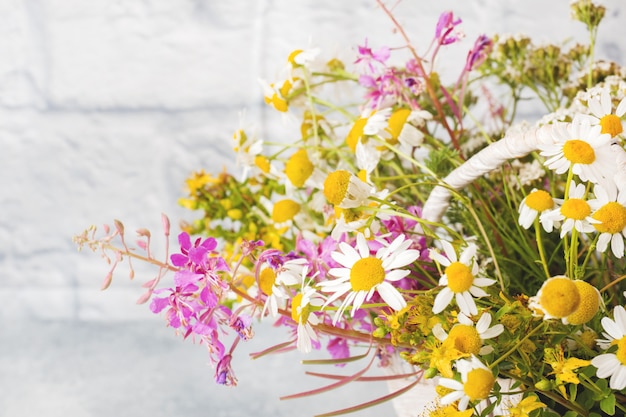 Bouquet of beautiful wildflowers in a basket on a gray surface with copy space.