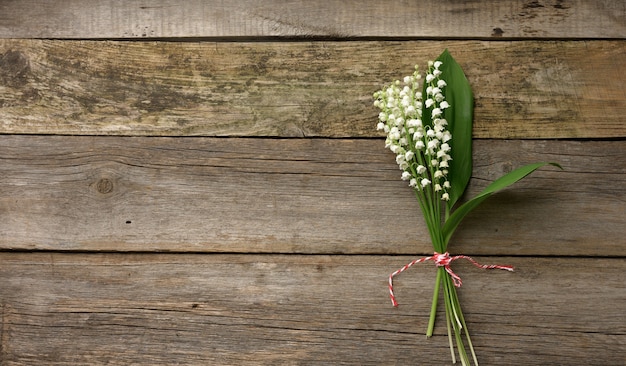 Bouquet of blooming lilies of the valley on a gray wooden surface, top view, copy space