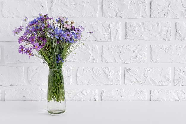 Bouquet of blue flowers in vase on table background