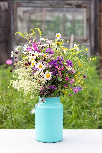 Bouquet of bright wild flowers in tin can vase on table outdoors rural scene Template for postcard Concept Womens day Mothers Day Hello summer or Hello spring