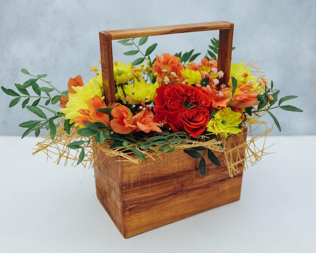 Bouquet of chrysanthemum peony rose and alstroemeria in a wooden gift box on a gray background Available in red orange and yellow