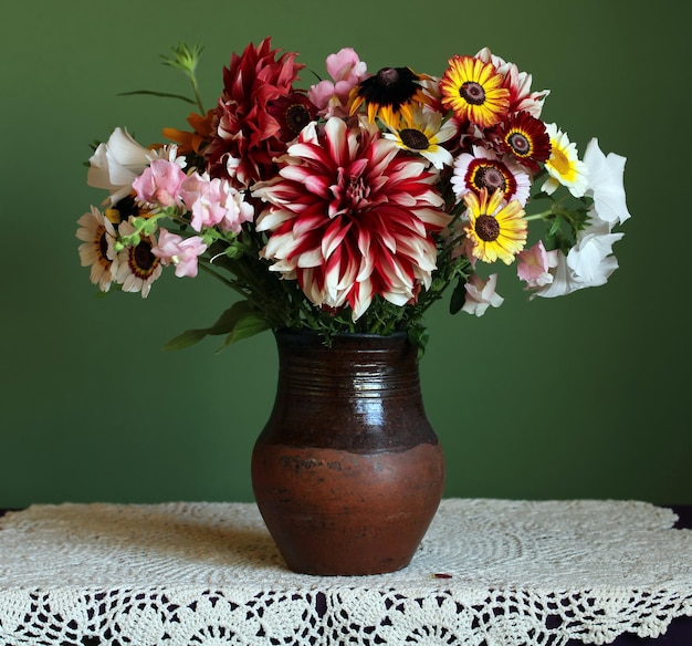 Bouquet in a clay jug on a green background