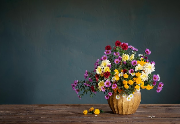 Bouquet of colorful chrysanthemums in vase on background dark wall