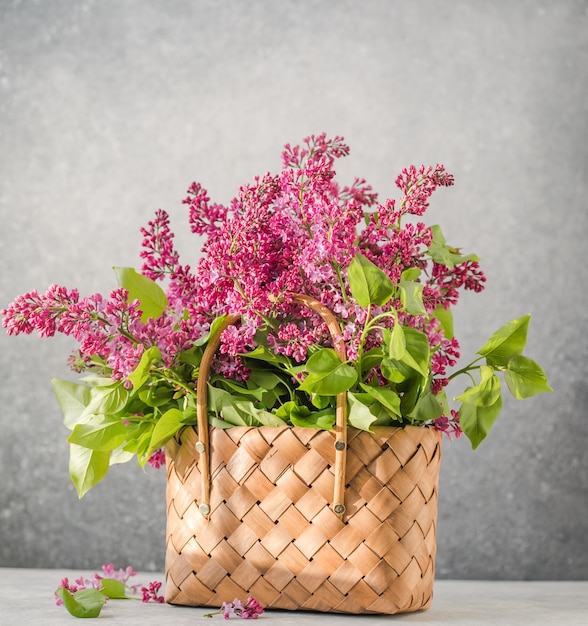 Bouquet of colorful lilac flowers in a wicker basket. Spring summer concept. Floral, interior, nature