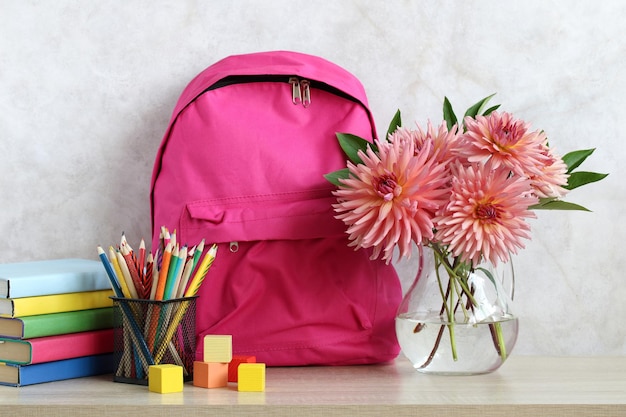 Bouquet of dahlias and a pink backpack on the desk