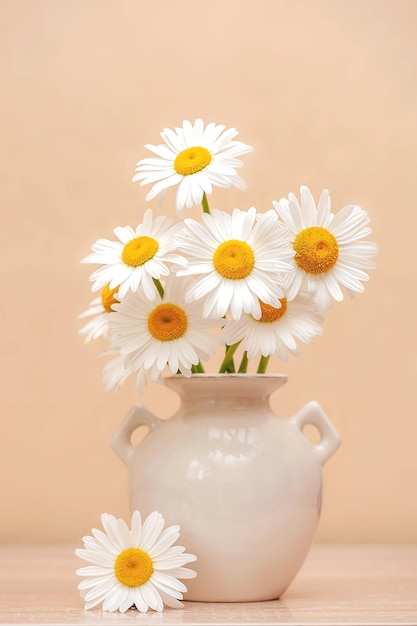 Bouquet of daisies in a vase on the table. vertical photo