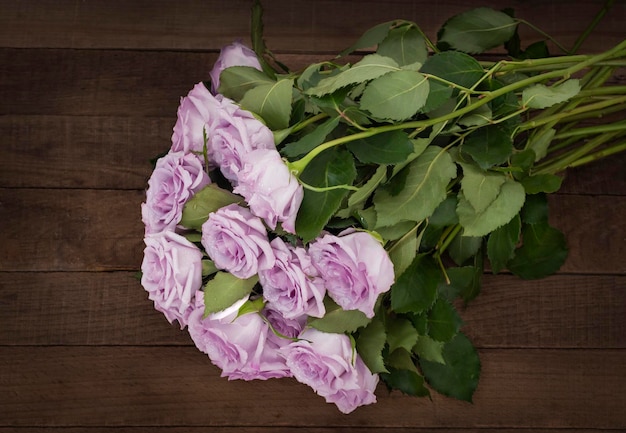 A bouquet of delicate purple roses on a background of dark wooden boards