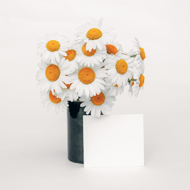 Bouquet of delicate white daisies in an elegant dark vase