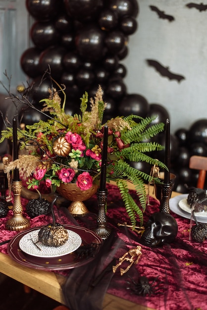 A bouquet of dried flowers on the table in honor of Halloween. A bat on a serving table.