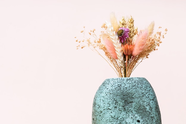 Bouquet of dried plants in ceramic vase on pink