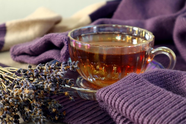 A bouquet of dry lavender next to a cup of hot tea on a pastel knitted sweater closeup