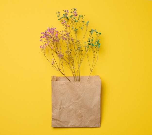 Bouquet of dry wildflowers on a yellow background top view