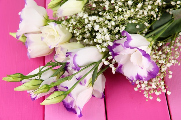 Bouquet of eustoma flowers on color wooden background