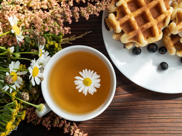 Bouquet of flowers, dessert on a white plate, a Cup of tea 