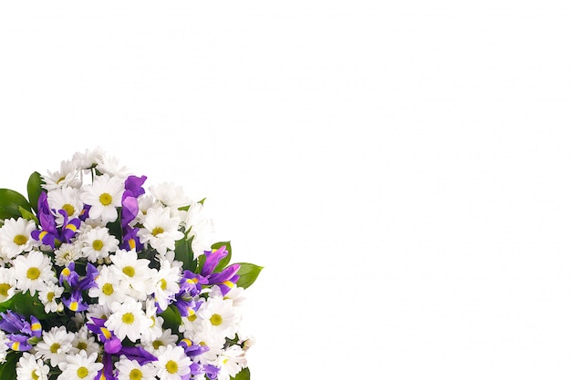 Bouquet of flowers from chamomiles and irises on a white wall