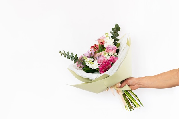 Bouquet of flowers in a stylish festive package in a male hand isolated on a white background