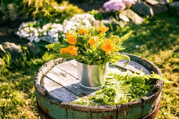 Bouquet of flowers in tin pots on an old wooden barrel. 