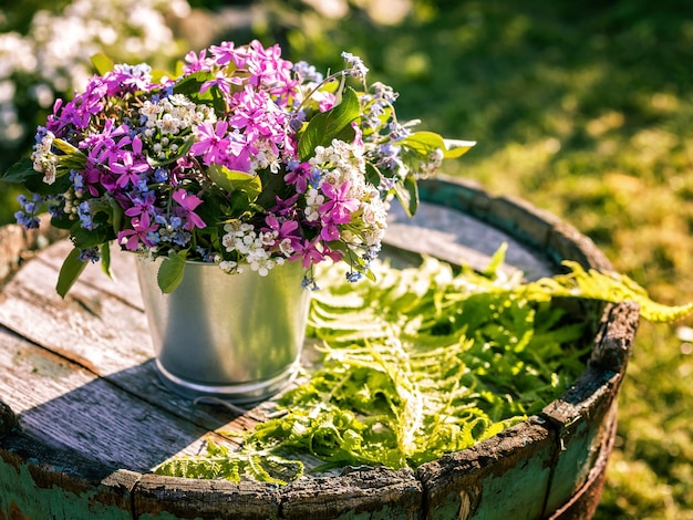 Bouquet of flowers in tin pots on an old wooden barrel.