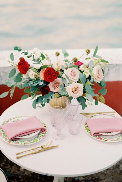 Bouquet of flowers in a vase stands on a table near plates and glasses