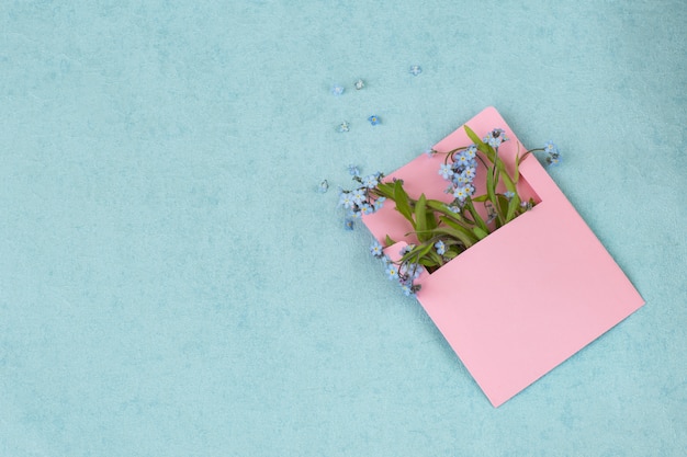 a bouquet of forget me nots in a pink envelope and free space for text