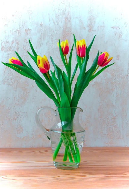 Bouquet of fresh pink tulips on a shelf in front of a stone wall Beautiful tulip flower bouquet