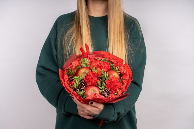 Bouquet of fruits and flowers in women's hands.