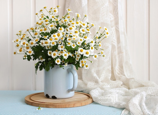 A bouquet of garden daisies in an enameled mug