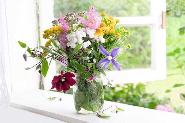 Bouquet of garden flowers on window sill