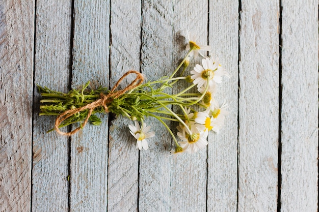 Bouquet of knitted little field daisies lie on an old light blue wooden