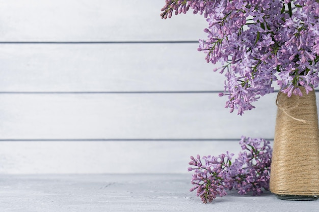 Bouquet of lilac flowers in vase on grey wooden background Copy space for backdrop