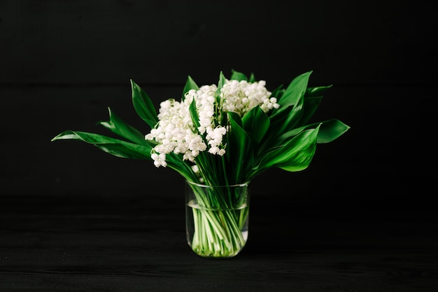 Bouquet of lilies of the valley on a black wooden background