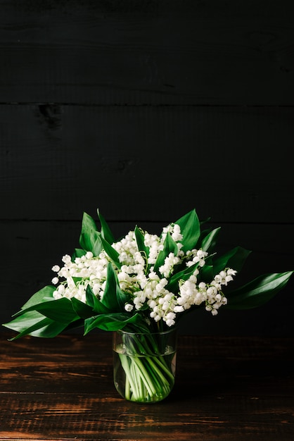 Bouquet of lilies of the valley on a black wooden background